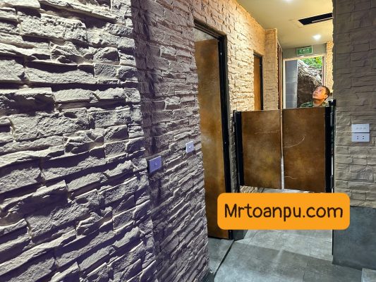 Thị trường vật liệu hoàn thiện nội ngoại thất đang chứng kiến bước chuyển mình mạnh mẽ từ các dòng vật liệu truyền thống nặng nề sang các giải pháp công nghệ cao siêu nhẹ. Trong số đó, xu hướng sử dụng vật liệu Polyurethane (PU) cấu trúc foam mật độ cao đang chiếm lĩnh các bản vẽ thiết kế hiện đại.
Nếu như khái niệm tổng thể về tấm pu giả đá đã khẳng định vị thế trong việc tái tạo vẻ đẹp thiên nhiên, thì hai biến thể chuyên sâu là tấm pu gạch thẻ và tấm pu đá thẻ lại mang đến giải pháp tinh tế, tỉ mỉ cho những mảng tường đòi hỏi tính điểm nhấn cao, kiến trúc phân lớp và sự linh hoạt trong thi công.
1. Tìm Hiểu Chi Tiết Bản Chất Kỹ Thuật
1.1 Tấm Pu gạch thẻ là gì?
Tấm PU gạch thẻ là dòng vật liệu trang trí dạng tấm đúc sẵn từ hợp chất Polyurethane mật độ cao (High-Density Polyurethane Foam), mô phỏng chính xác hình dáng, kích thước và bề mặt của các mảng gạch thẻ kiến trúc (gạch móng, gạch xây thô, gạch gốm).
Thay vì phải ốp từng viên gạch đơn lẻ tốn hàng tuần lễ, sản phẩm này tích hợp hàng trăm "viên gạch thẻ" trên một khối tấm lớn với các đường mạch (ron) được định hình chuẩn xác tuyệt đối từ khuôn đúc.
1.2 Tấm Pu đá thẻ là gì?
Tương tự như biến thể gạch thẻ, tấm pu đá thẻ tái hiện cấu trúc của các thanh đá tự nhiên được chẻ nhỏ và ghép lớp (như đá chẻ, đá slate, đá tăm). Bề mặt của tấm đá thẻ sở hữu độ gồ ghề, góc cạnh chớp nhấp chênh lệch chiều sâu rõ rệt, tạo hiệu ứng thị giác 3D vô cùng chân thực dưới ánh sáng đèn trang trí